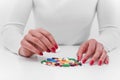 Woman chooses medicine from a handful of different color tablets. Royalty Free Stock Photo