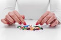 Woman chooses medicine from a handful of different color tablets. Royalty Free Stock Photo