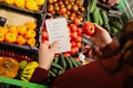 woman follows shopping list when buying fruits and vegetables in supermarket. Royalty Free Stock Photo