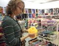 A woman chooses the yarn in the store. A woman makes a purchase yellow yarn for knitting in the store.