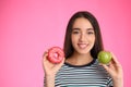 Woman choosing between apple and doughnut on pink background Royalty Free Stock Photo