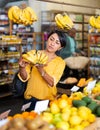 Woman choosing bananas in fruit and vegetable section of supermarket Royalty Free Stock Photo