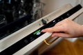 Woman choosing eco mode program on digital control panel of the dishwasher. Royalty Free Stock Photo