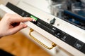 Woman choosing eco mode program on the digital control panel of the dishwasher. Royalty Free Stock Photo