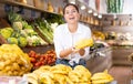 Woman choosing fresh bananas in fruit and vegetable section of supermarket Royalty Free Stock Photo