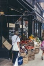 A woman choosing fruits in the crates installed just outside the Artichoke fruit and vegetable shop in London