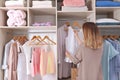 Woman choosing outfit from large wardrobe closet with stylish clothes