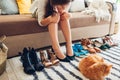 Woman choosing shoes and trying them on at home. Hard choice to make from sandals, heels and flats