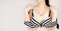 Woman choosing stripe lace lingerie. Sexy boob. Beautiful female holding a bra. Woman is breast in beige underwear or sport bra Royalty Free Stock Photo