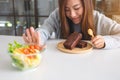 A woman choosing to eat brownie cake and making hand sign to refuse a vegetables salad Royalty Free Stock Photo