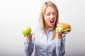Woman choosing to eat burger instead of apple