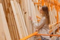 Woman choosing wooden plank in hardware store. Building materials for home renovation Royalty Free Stock Photo