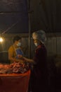 A woman is chopping beef in her stall