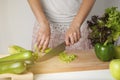 Woman chopping celery vegetable, preparing food in her kitchen, she is cutting fresh celery on a cutting board with a knife. Woode Royalty Free Stock Photo