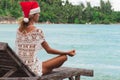 Woman in christmas hat meditating in a yoga pose at thel beach Royalty Free Stock Photo