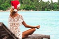 Woman in christmas hat meditating in a yoga pose at thel beach Royalty Free Stock Photo
