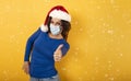 Woman with Christmas hat is optimistic about the defeat of covid 19 coronavirus. yellow background.