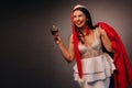 A woman in a Christmas hat and white dress, holding a glass and a red fur coat in her hands, on a black background, Christmas, Royalty Free Stock Photo