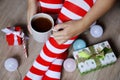 Woman in Christmas knee socks sitting with cup of hot cocoa in hands