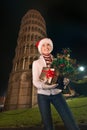 Woman with Christmas tree and gift box near Leaning Tower, Pisa Royalty Free Stock Photo