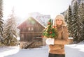 Woman with Christmas tree standing in front of mountain house Royalty Free Stock Photo