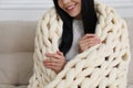 Woman with chunky knit blanket on sofa at home, closeup Royalty Free Stock Photo