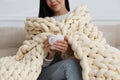 Woman with chunky knit blanket on sofa at home, closeup Royalty Free Stock Photo