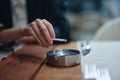 A woman with a cigarette in her hands shakes the ashes into an ashtray, close-up Royalty Free Stock Photo