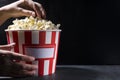 Woman in the cinema eating popcorn.A large bucket of salty popcorn against black wall.Empty space fo text Royalty Free Stock Photo