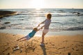 woman is circling the hands of a little boy, mom and son are having fun on the beach at sunset Royalty Free Stock Photo