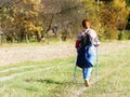 A woman in city clothes stroll through the summer`s grass in the rays of sunlight. Healthy lifestyle. Sport`s event. A personal ex