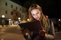 Woman in the city at night holding tablet, reading something. Royalty Free Stock Photo