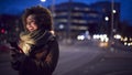 Woman On City Street At Night Ordering Taxi Using Mobile Phone App