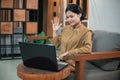 woman in civilian uniform use laptop while sitting with hand gestures to say hello