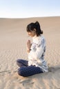 A woman clasping hands at the beach at sunset. Namaste pose