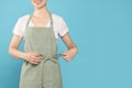 Woman in clean apron with pattern on light blue background, closeup. Space for text Royalty Free Stock Photo