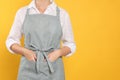 Woman in clean apron with pattern on orange background, closeup. Space for text Royalty Free Stock Photo