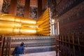 Woman cleaning a big buddha gold statue at Wat Pho, Bangkok, Thailand Royalty Free Stock Photo