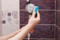 Woman cleaning an calcified shower head in domestic bathroom with small brush