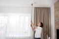 Woman cleaning ceiling with a mop. Housewife cleaning living room