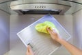 Woman Cleaning Cooker Hood With Rag In Kitchen At Home.