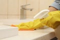 Woman cleaning counter with detergent and rag in bathroom Royalty Free Stock Photo