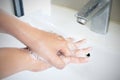 The woman cleaning dirty hands by washing hand with foam soap and water in white sink in bathroom Royalty Free Stock Photo