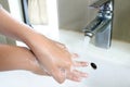 The woman cleaning dirty hands by washing hand with foam soap and water in white sink in bathroom Royalty Free Stock Photo