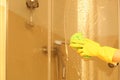 Woman cleaning door of shower cabin in bathroom