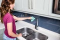 Woman cleaning faucet at kitchen sink Royalty Free Stock Photo