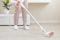 Woman cleaning floor with wireless vacuum cleaner in living room Royalty Free Stock Photo