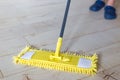 Woman cleaning floor with yellow mop at home. Microfiber mop isolated on white wooden floor background, closeup, indoors Royalty Free Stock Photo