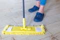 Woman cleaning floor with yellow mop at home. Microfiber mop isolated on white wooden floor background, closeup, indoors Royalty Free Stock Photo