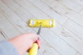 Woman cleaning floor with yellow mop at home. Microfiber mop isolated on white wooden floor background, closeup, indoors Royalty Free Stock Photo